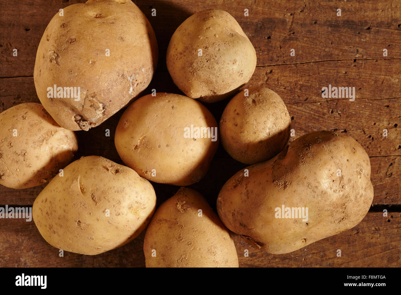 Patate intere su uno sfondo di legno Foto Stock