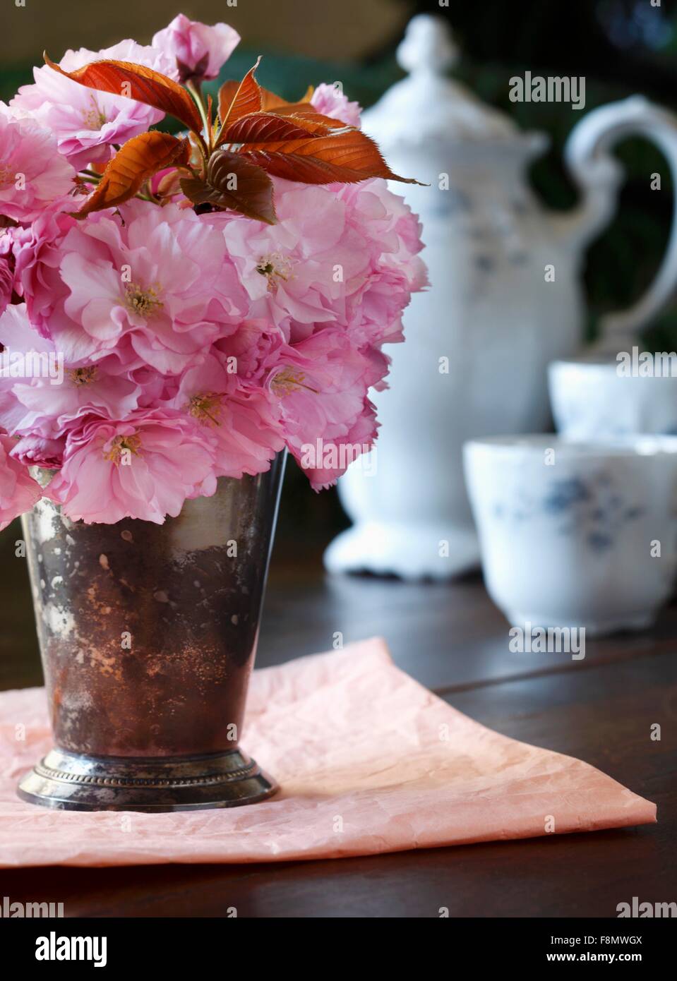 Fiori di Ciliegio in un vaso con antichi Impostazione di tè in background Foto Stock