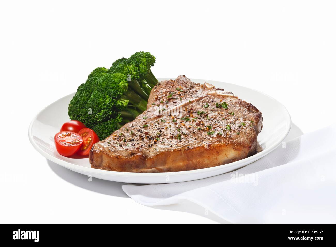 Condito T-Bone Steak con pomodorini e broccoli su sfondo bianco Foto Stock