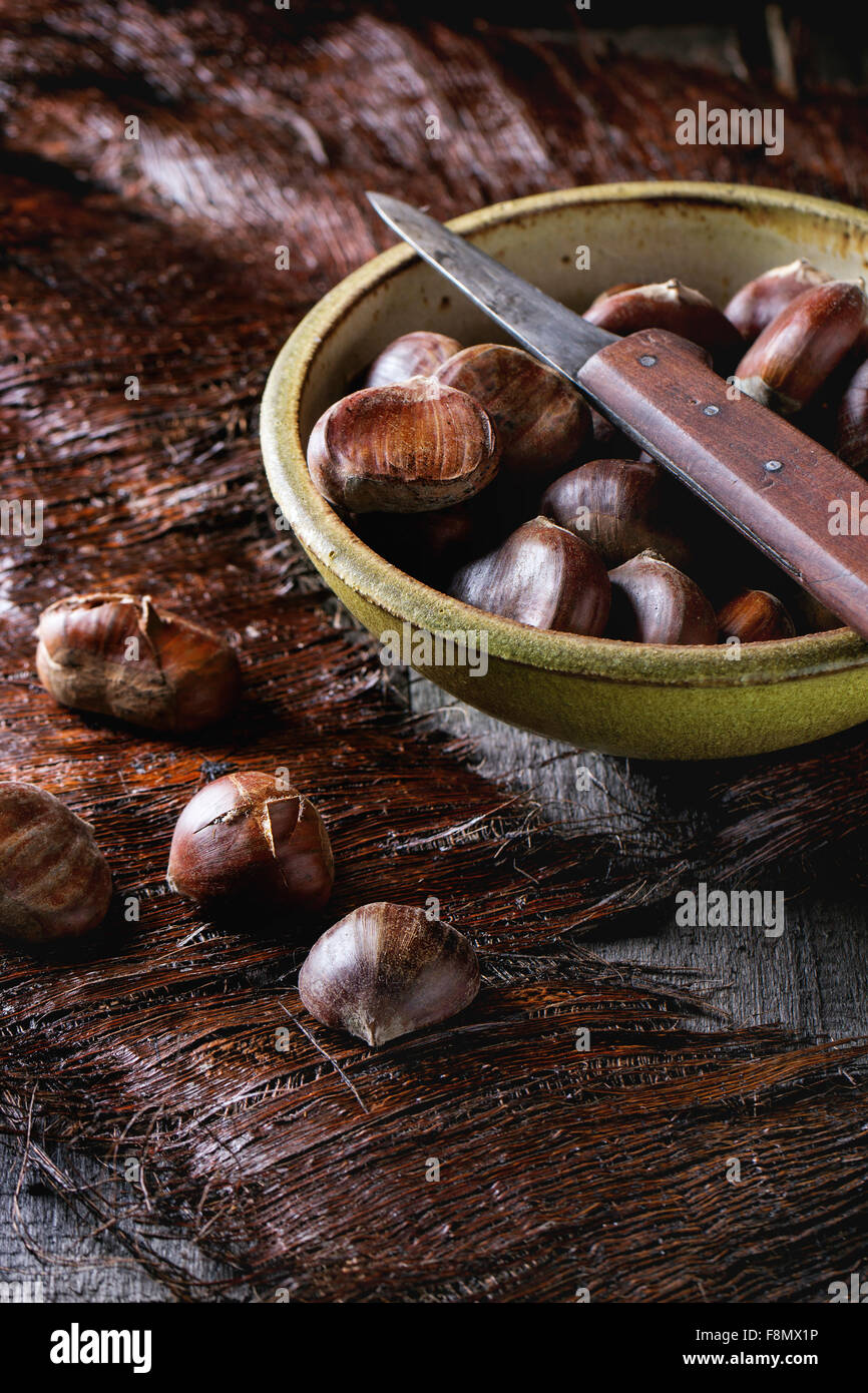 Vaso in ceramica di materie commestibili di castagne con coltello vintage su un tavolo di legno Foto Stock