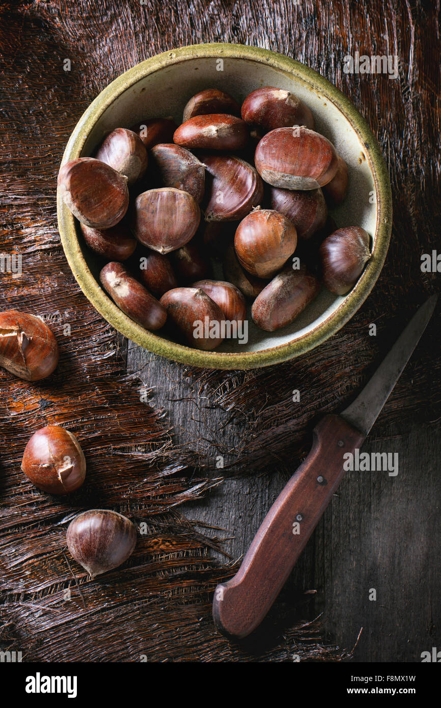 Vaso in ceramica di materie commestibili di castagne con coltello vintage su un tavolo di legno Foto Stock