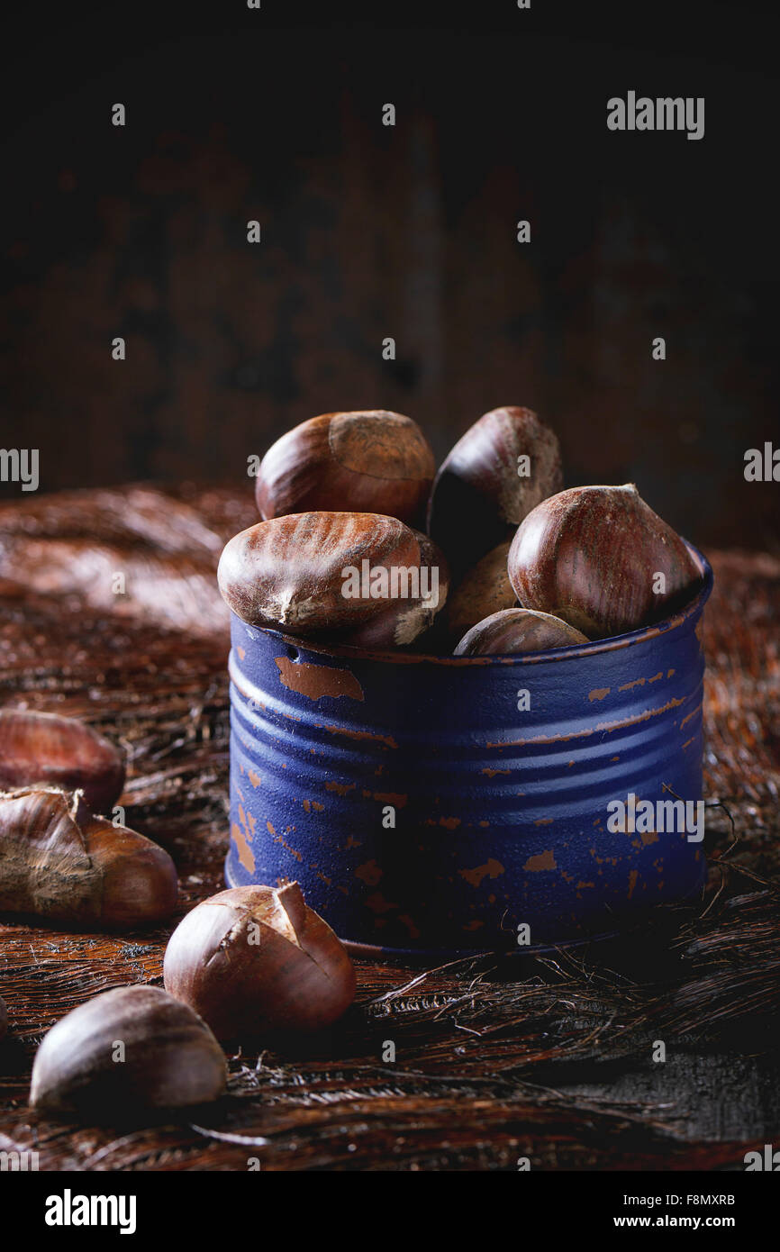 Viola barattolo di latta con materie prime castagne commestibili su un tavolo di legno. Vista laterale Foto Stock