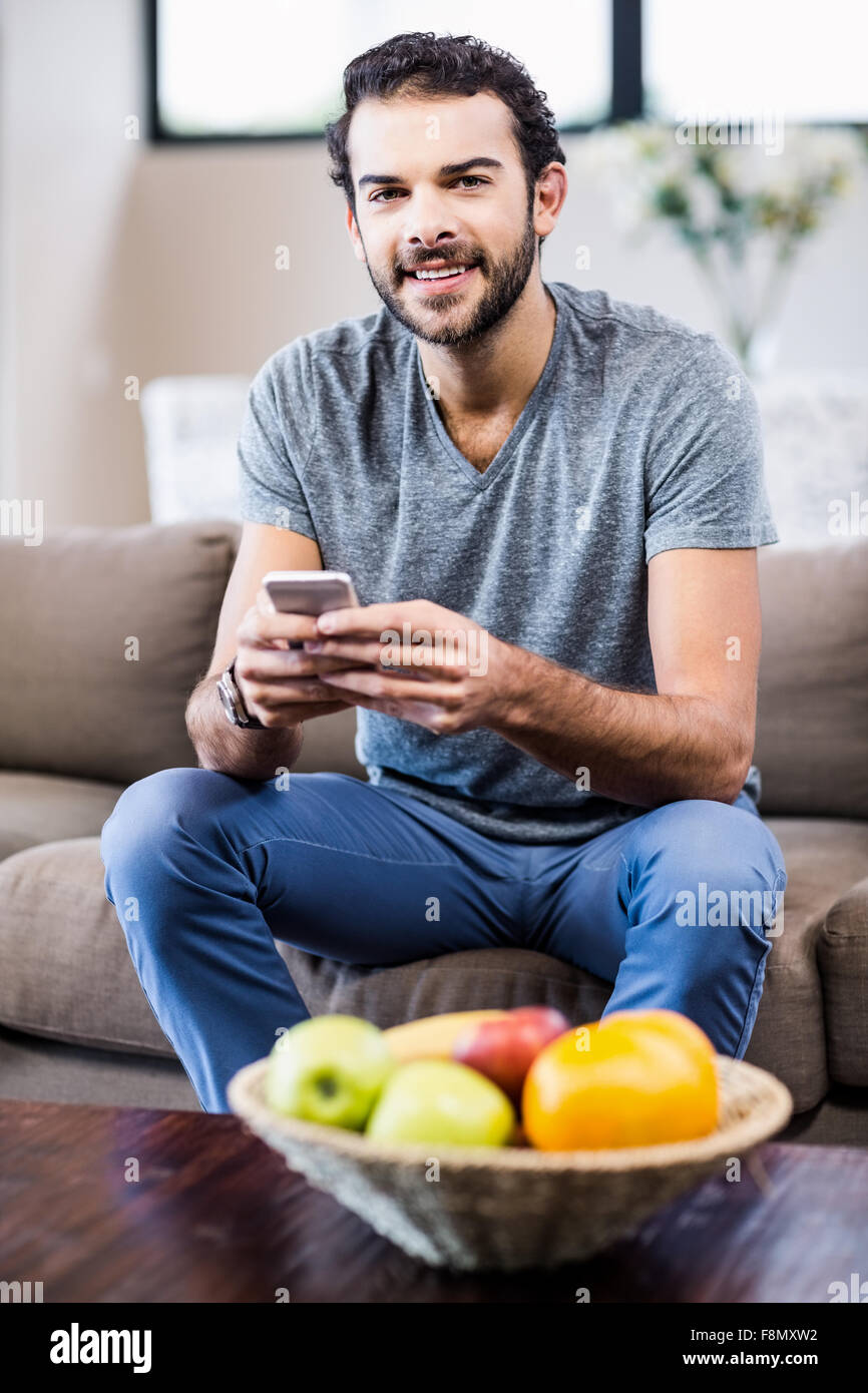Attraente uomo utilizza lo smartphone sorridente in telecamera Foto Stock