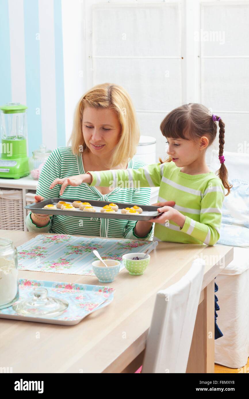 Una madre e figlia tenendo un vassoio da forno di inceppamento crudi biscotti Foto Stock