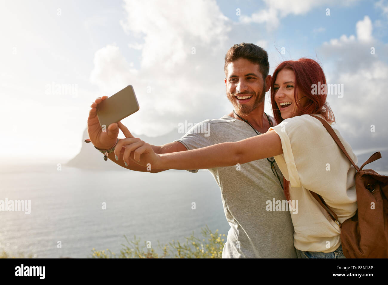 Ridere una giovane coppia in vacanza facendo selfie con il telefono cellulare. Coppia giovane dalla baia di prendere un ritratto selfie con smart p Foto Stock