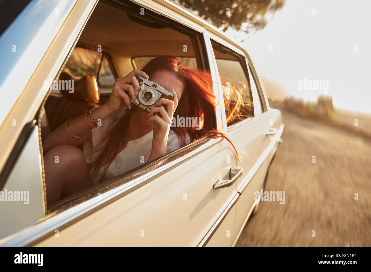 Colpo di giovane donna di scattare le foto mentre è seduto in un'auto. Femmina di catturare un perfetto viaggio su strada in questo momento. Foto Stock