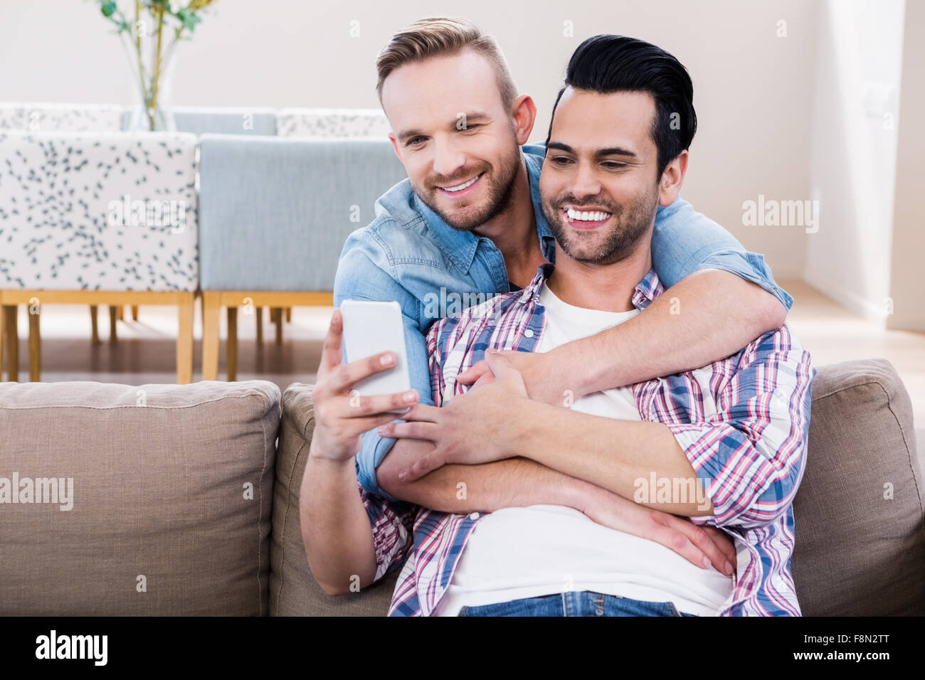 Coppia gay rilassante sul lettino usando il telefono Foto Stock