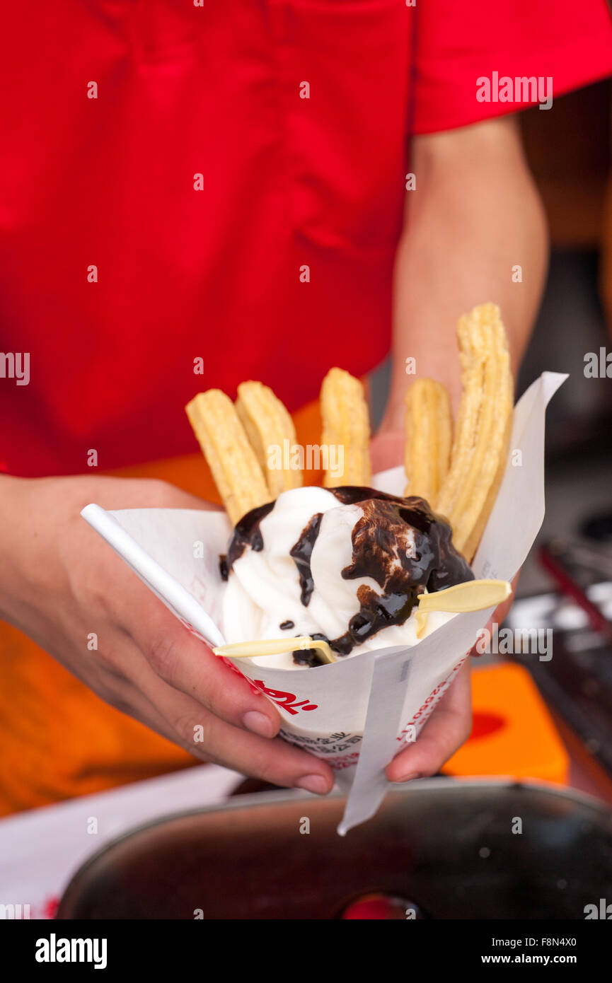 Venditore azienda Takeaway dessert di gelato e di pasta fritta bastoni Foto Stock