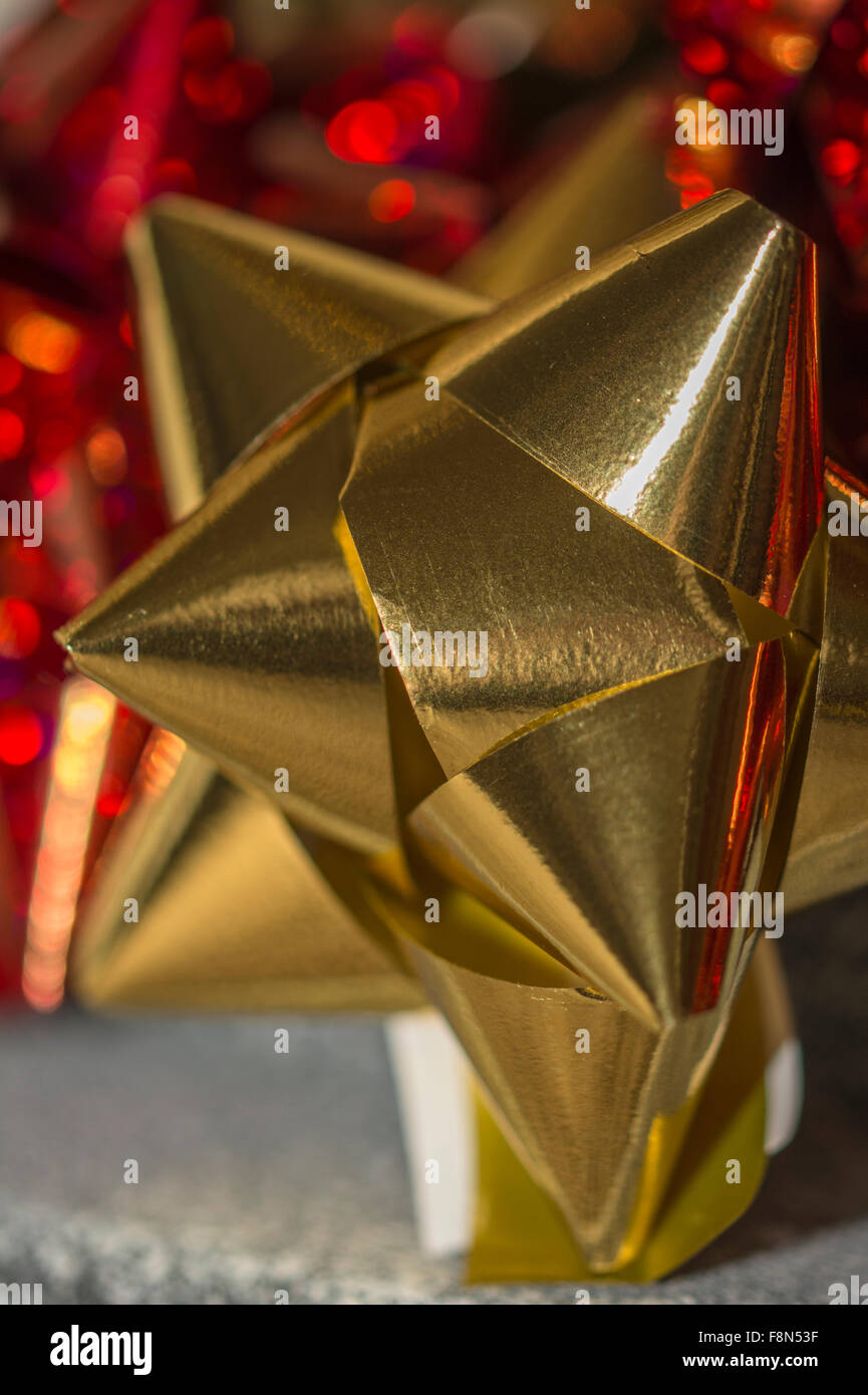 Close up di un oro regalo di Natale prua con red bokeh di fondo Foto Stock