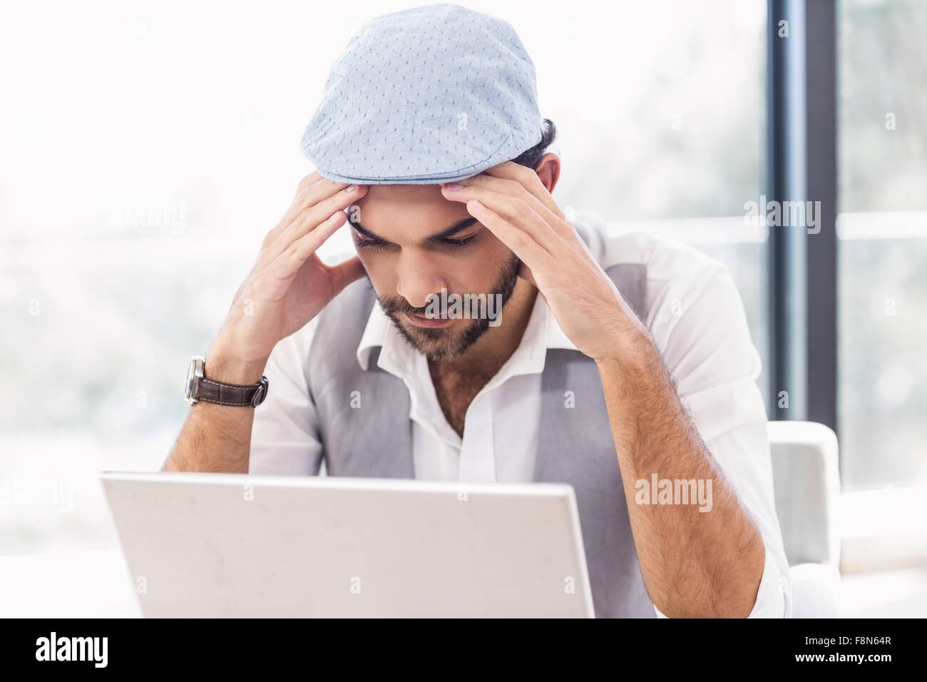 Preoccupato uomo con le mani sul suo viso mentre guarda il computer portatile Foto Stock