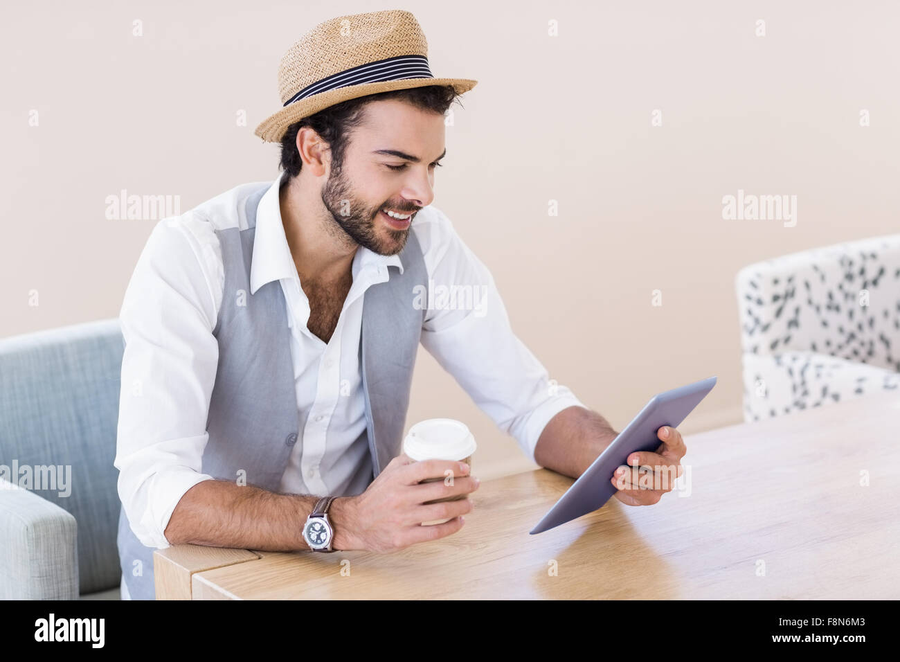 Uomo sorridente holding tablet e la tazza monouso Foto Stock