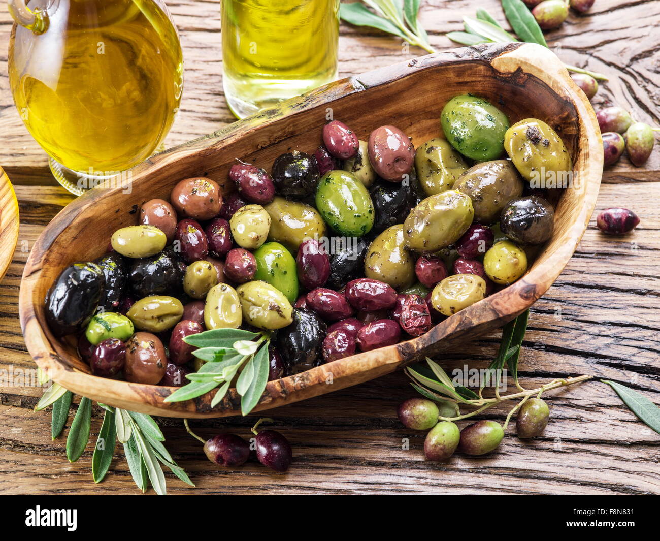 Tutta le olive da tavola nella ciotola di legno sul tavolo. Foto Stock