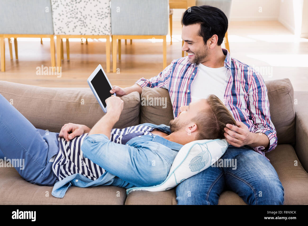 Coppia gay rilassante sul lettino usando tablet Foto Stock