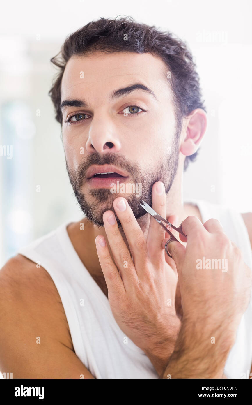 Uomo concentrato il suo taglio di barba con le forbici Foto Stock