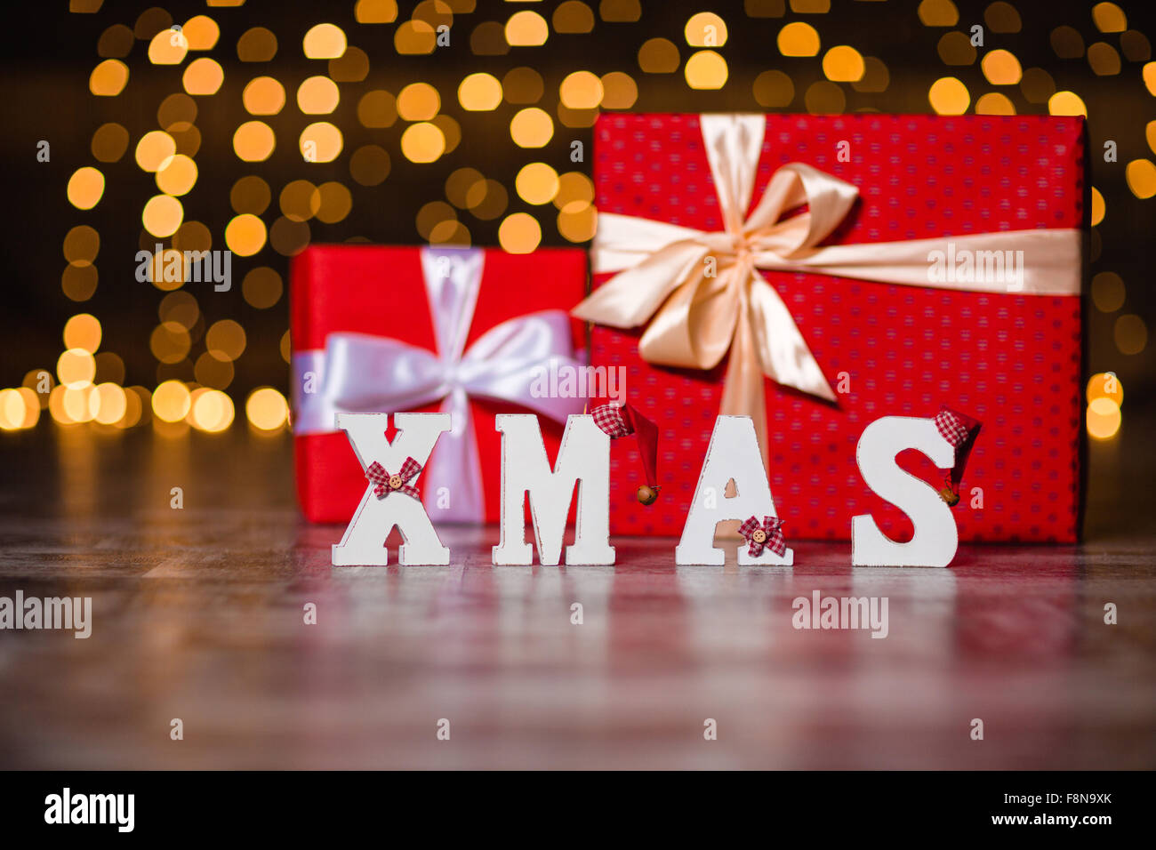 Xmas decorata di bianco di testo e le caselle presenti in piedi sul pavimento su vacanze sfondo luci Foto Stock