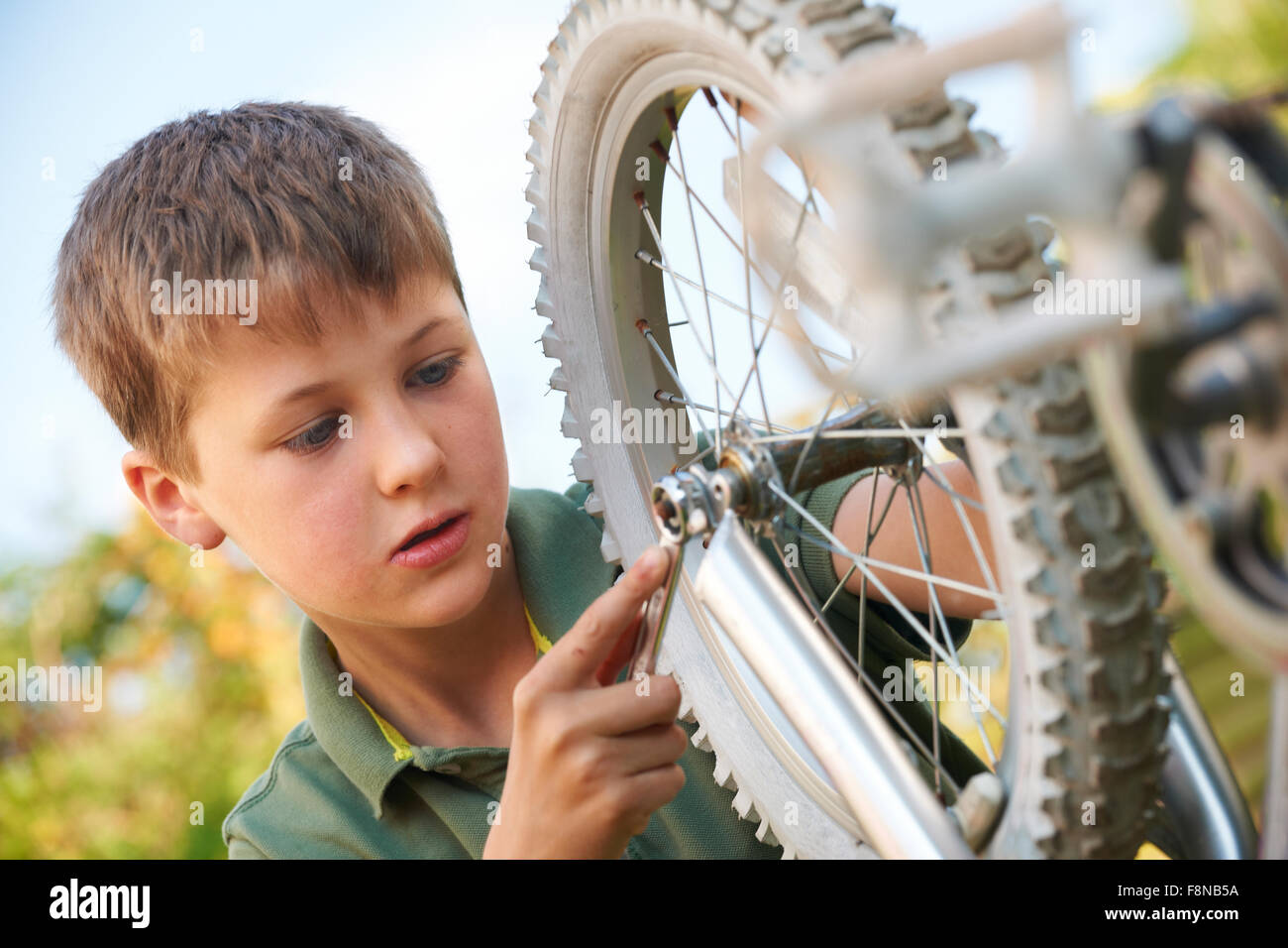 Ragazzo che fissa la ruota di bicicletta Foto Stock