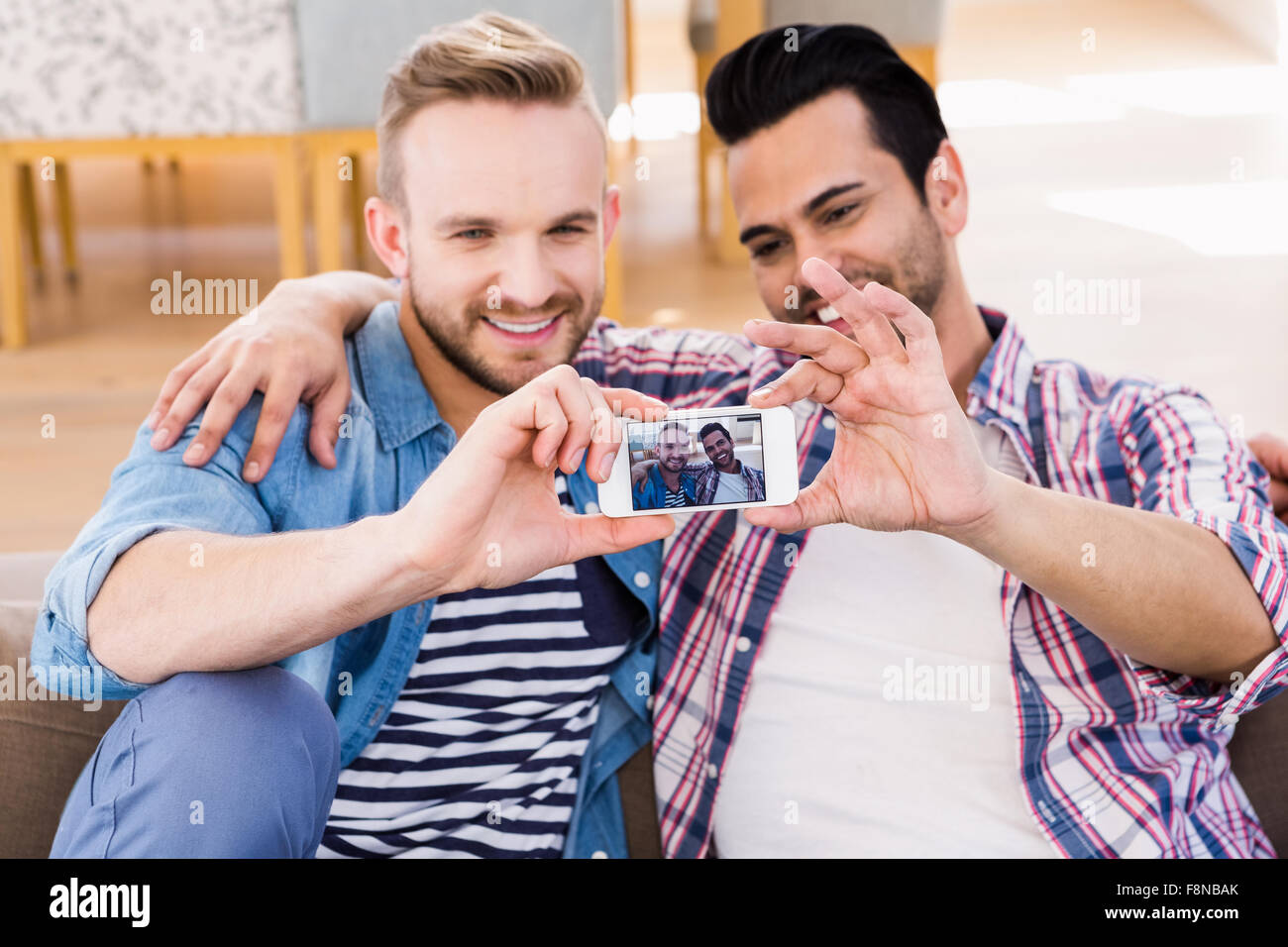 Coppia gay rilassante sul lettino tenendo selfie Foto Stock