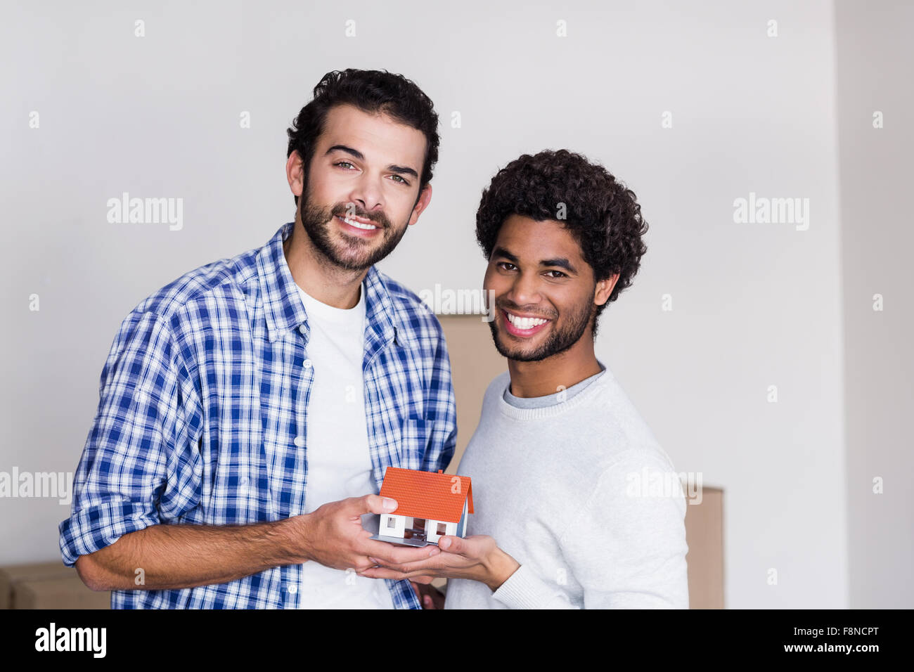 Felice coppia gay tenendo in miniatura Modello di casa Foto Stock