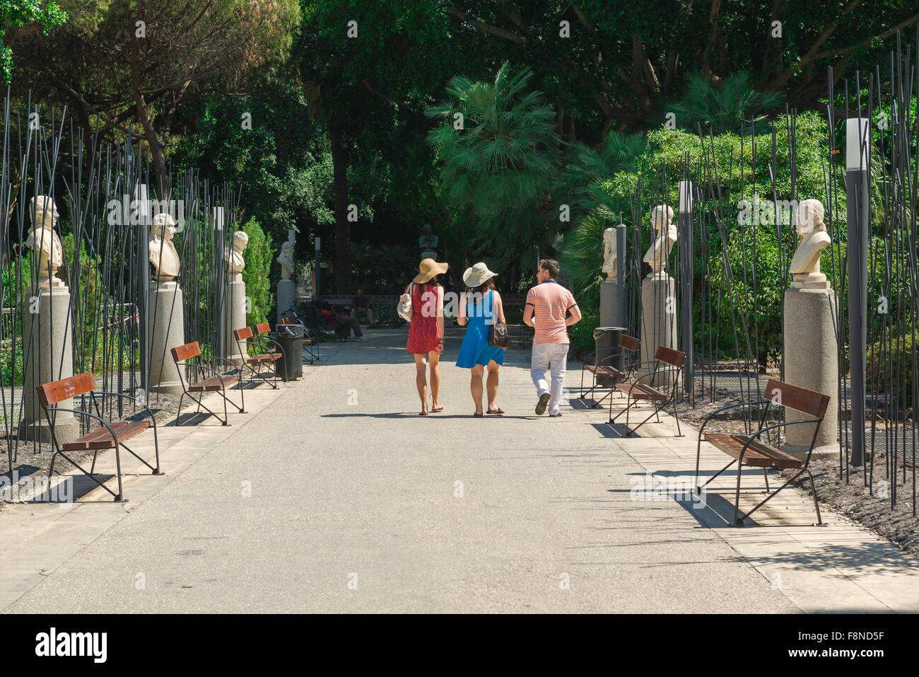 Amici walking park estate, vista posteriore delle donne e un uomo a piedi attraverso la Villa Bellini, il più grande parco e giardini di Catania, Sicilia, Italia. Foto Stock