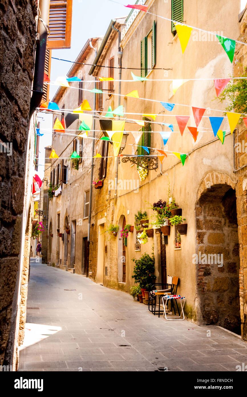 Colorati bandiere di partito onda in un piccolo vicolo durante una festa del paese a Pitigliano, Italia Foto Stock