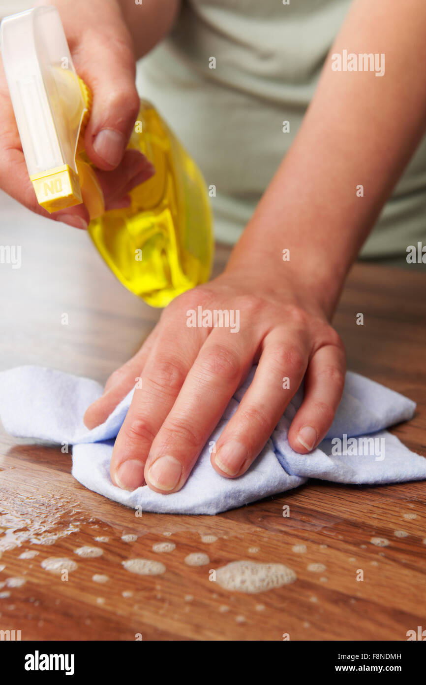 Donna che utilizza Spray per la pulizia di una superficie di legno Foto Stock