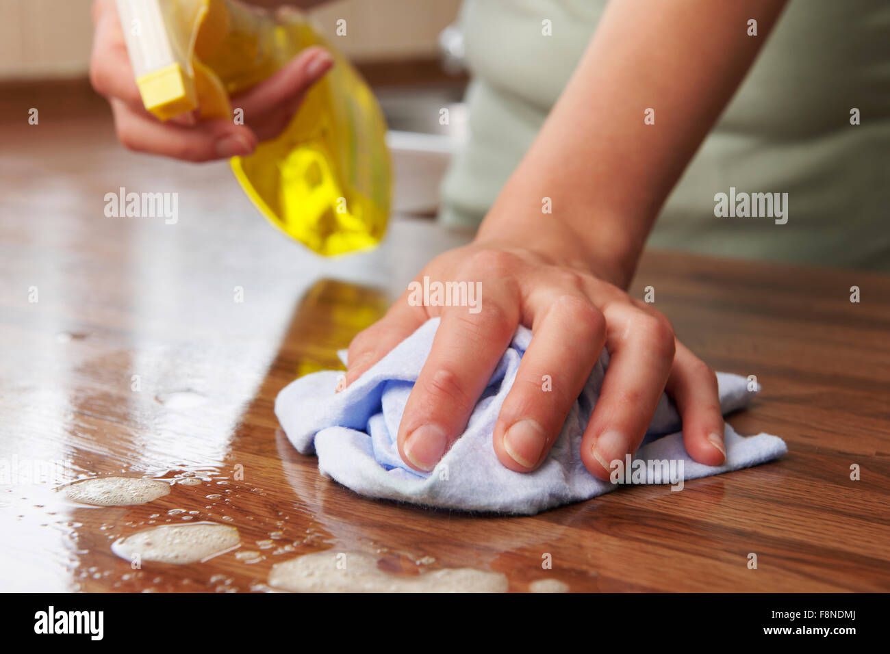 Donna che utilizza spruzzare il detergente sulla superficie di legno Foto Stock