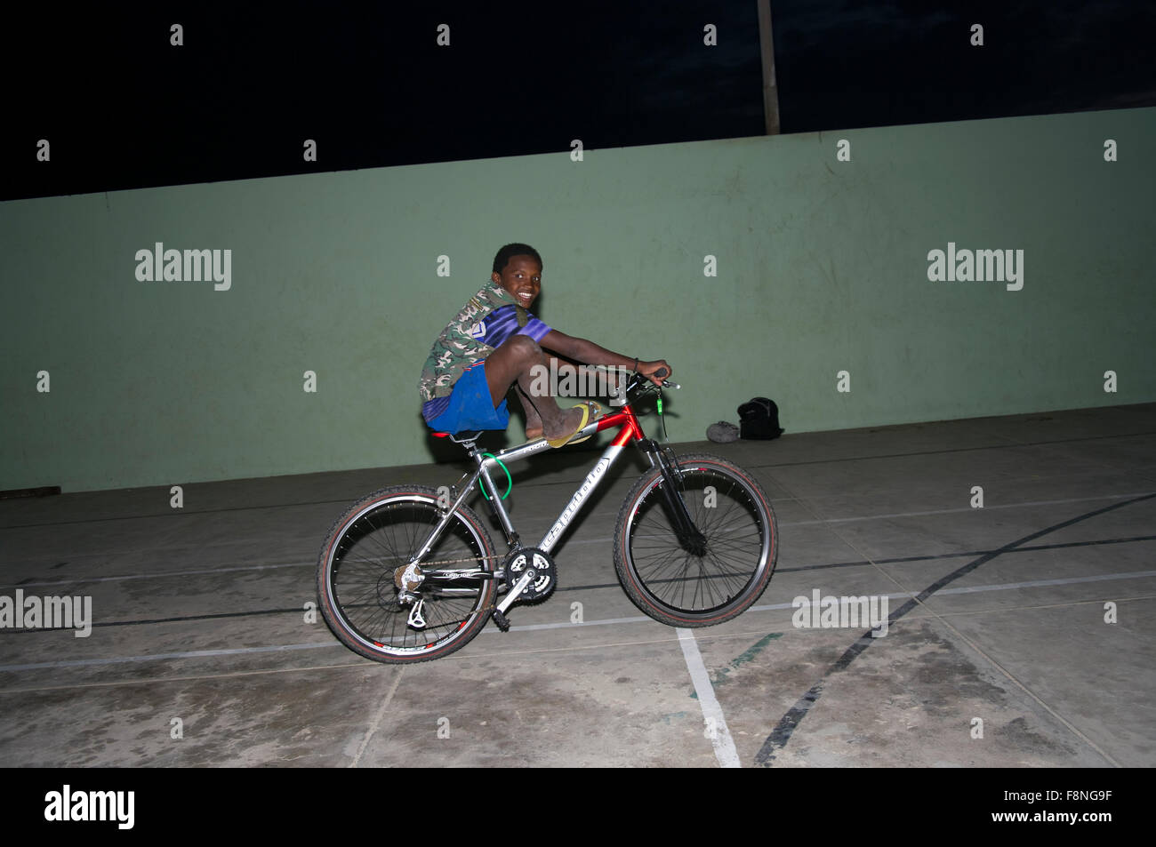 Ragazzo africano sorridente su una bicicletta con le sue gambe in su sull'isola repubblica di Capo Verde Foto Stock