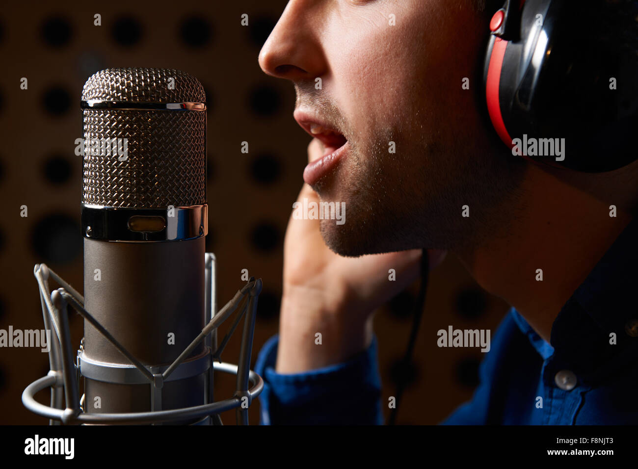 Vocalist maschio cantare nel microfono in studio di registrazione Foto Stock