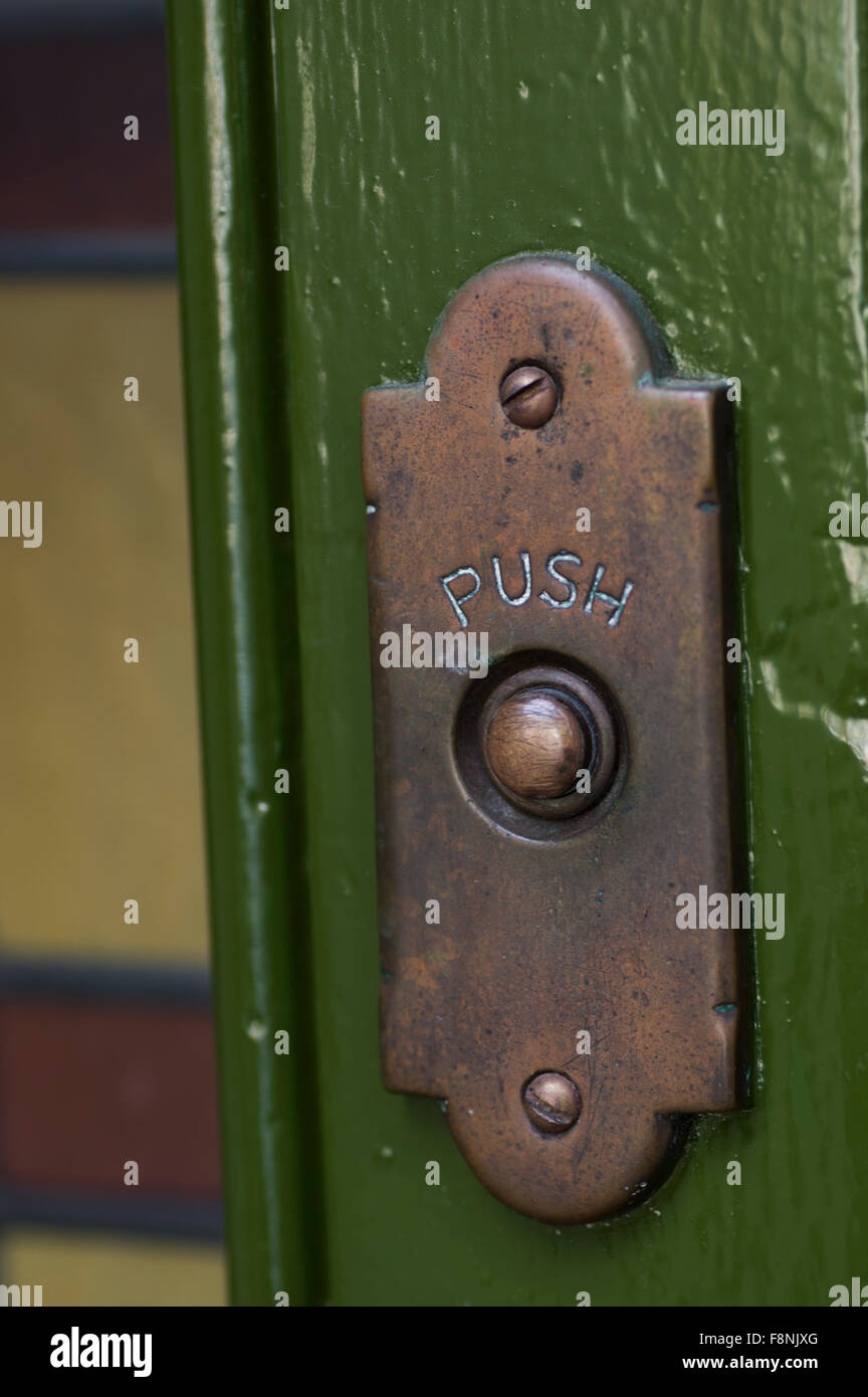 Vecchio, offuscata ottone campanello della porta su un muro verde Foto Stock