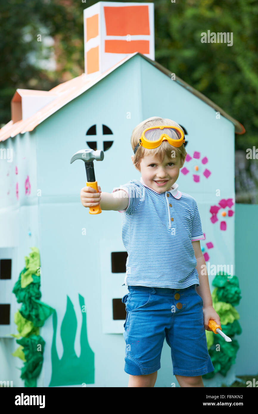 Ragazzo giovane fingendo di fissare Playhouse di cartone Foto Stock