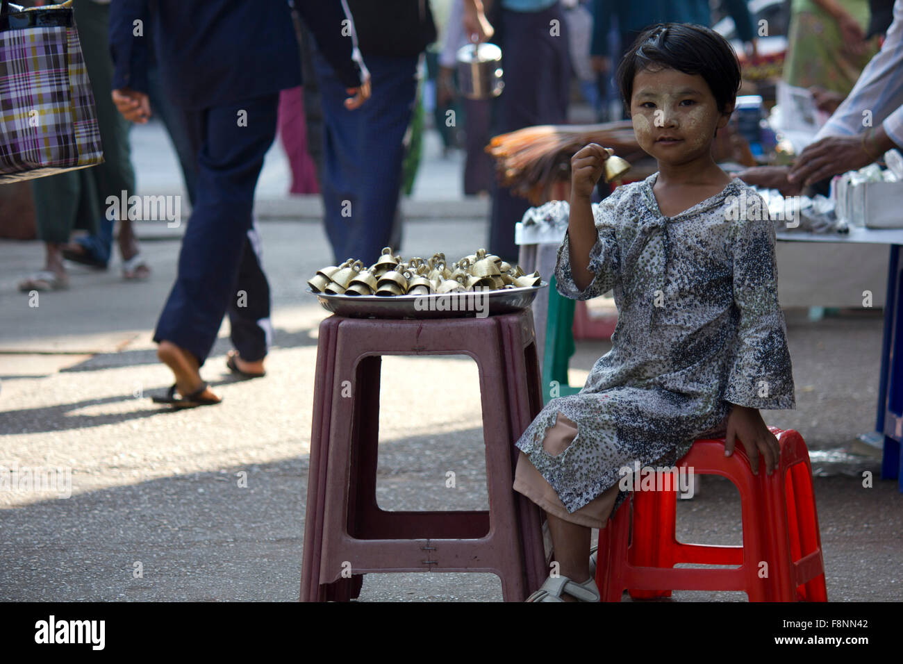 Giovani campane venditore. Una giovane ragazza vendendo le campane in strada di Yangoon, nel Myanmar (Birmania) In faccia ha il tipico sabbia Foto Stock