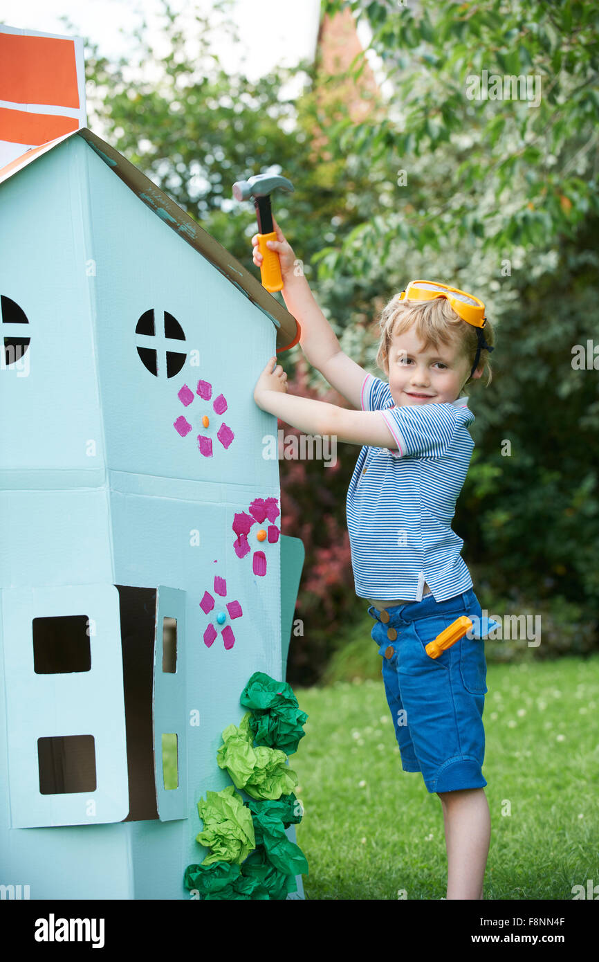 Ragazzo giovane fingendo di fissare Playhouse di cartone Foto Stock