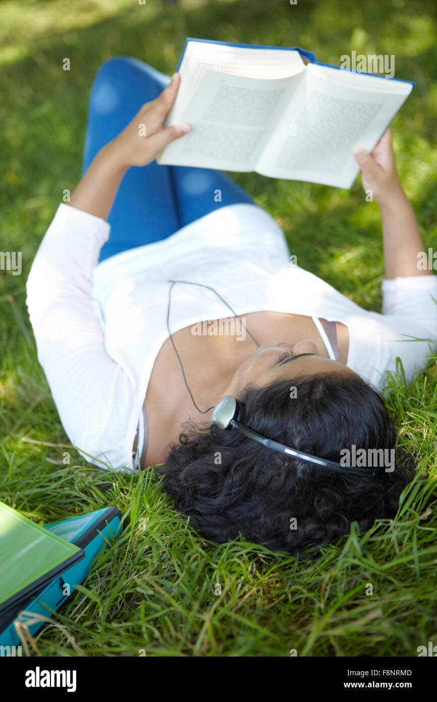 Spensierato studente di revisione e di ascolto di musica in posizione di parcheggio Foto Stock