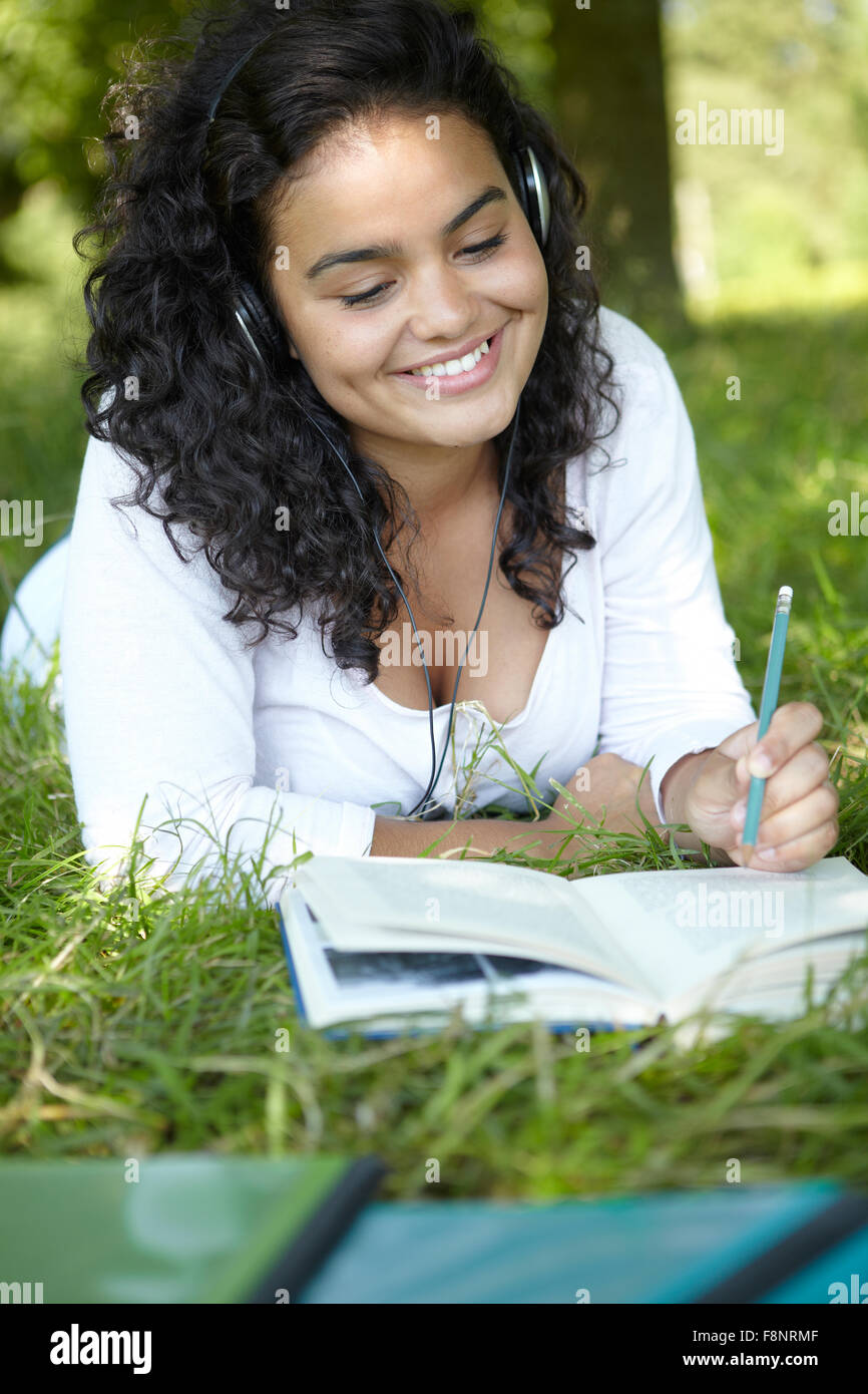 Spensierato studente di revisione e di ascolto di musica in posizione di parcheggio Foto Stock