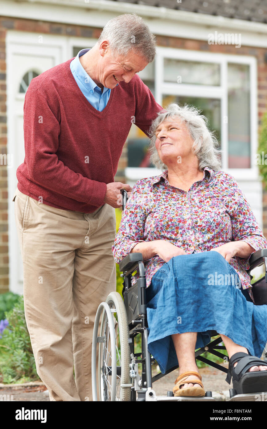Senior uomo spingendo la moglie disabili in sedia a rotelle Foto Stock