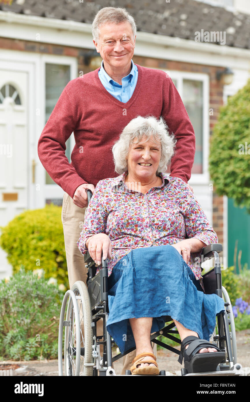 Senior uomo spingendo la moglie disabili in sedia a rotelle Foto Stock