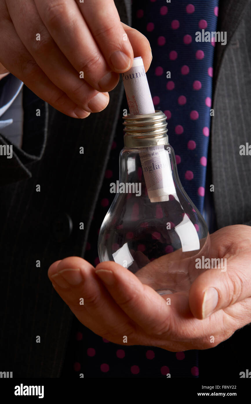 Imprenditore mettendo Sterling nota nel bulbo di luce Foto Stock