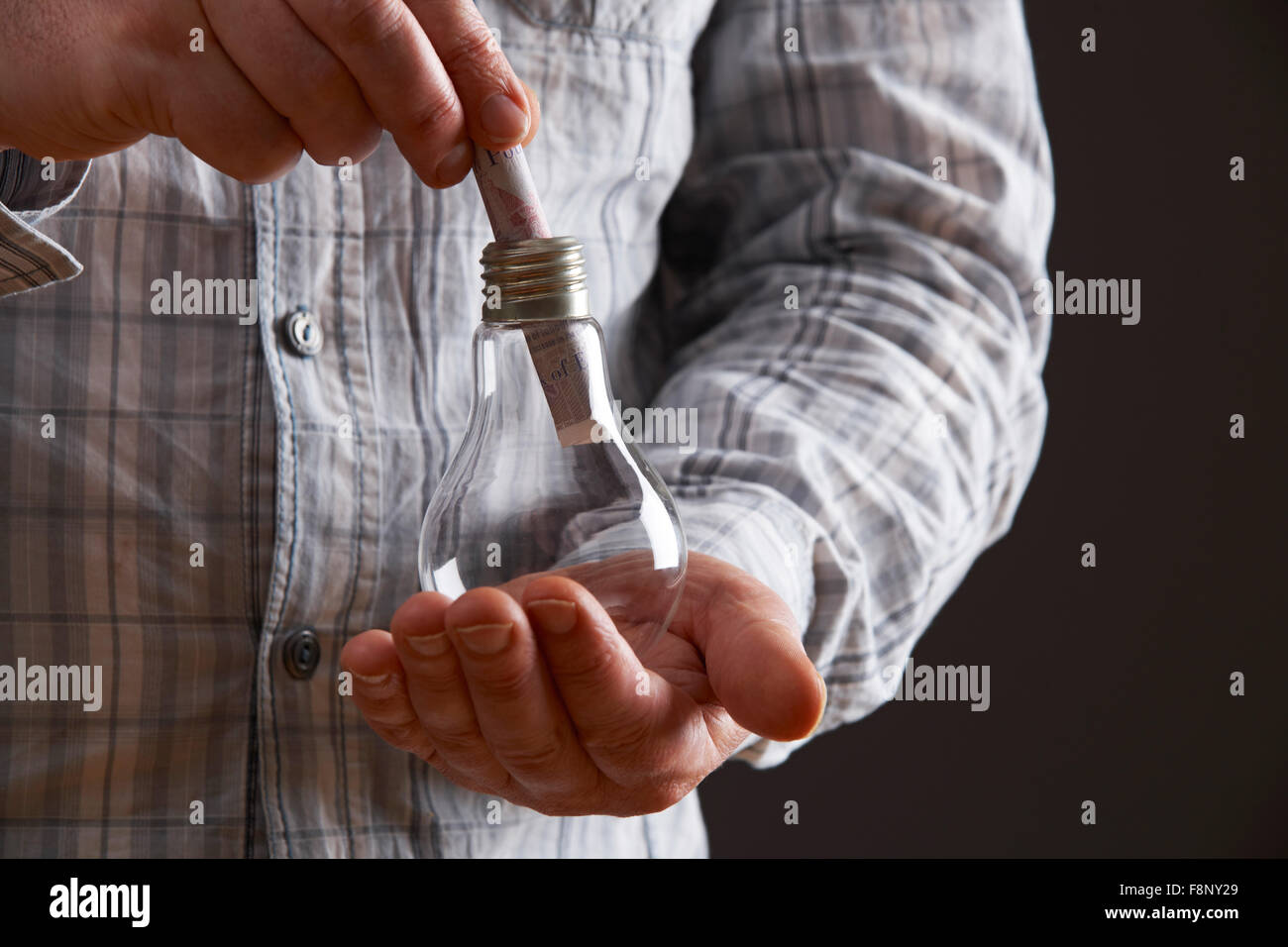 L'uomo mettendo Sterling nota nel bulbo di luce Foto Stock