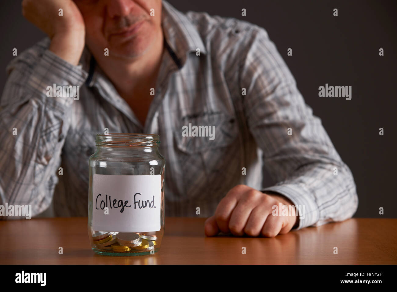 Premuto Un uomo guarda il vaso vuoto etichettati College Fund Foto Stock