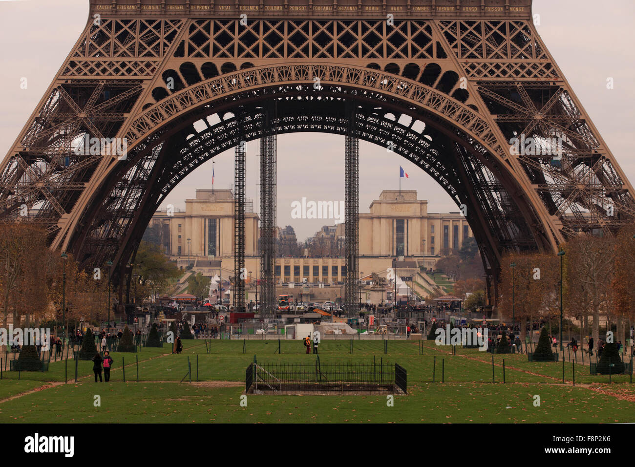 La folla si radunano sotto gli enormi gambe in metallo della Torre Eiffel a Parigi, Francia. Foto Stock