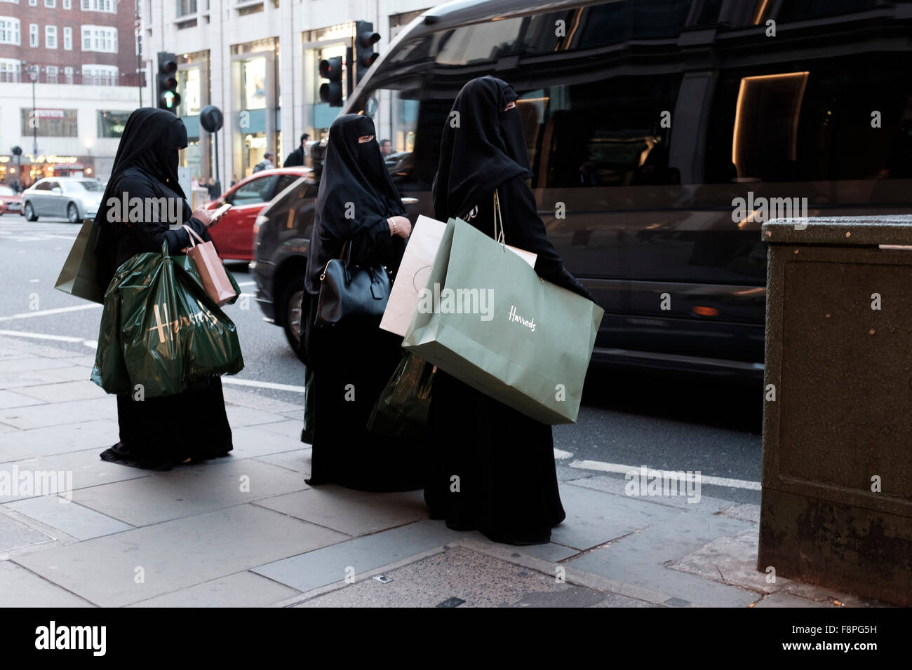 Ricchi di medio-poppa donne con Harrods borse per lo shopping in attesa di taxi,Knightsbridge, Londra, Inghilterra Foto Stock