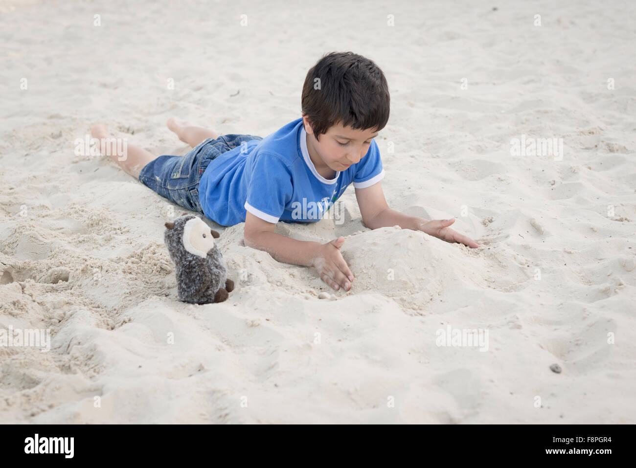 Ragazzo giocando da solo nella sabbia Foto Stock