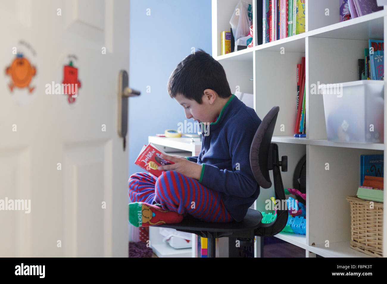 Scolaro,6 anni,leggendo un libro nella sua stanza Foto Stock