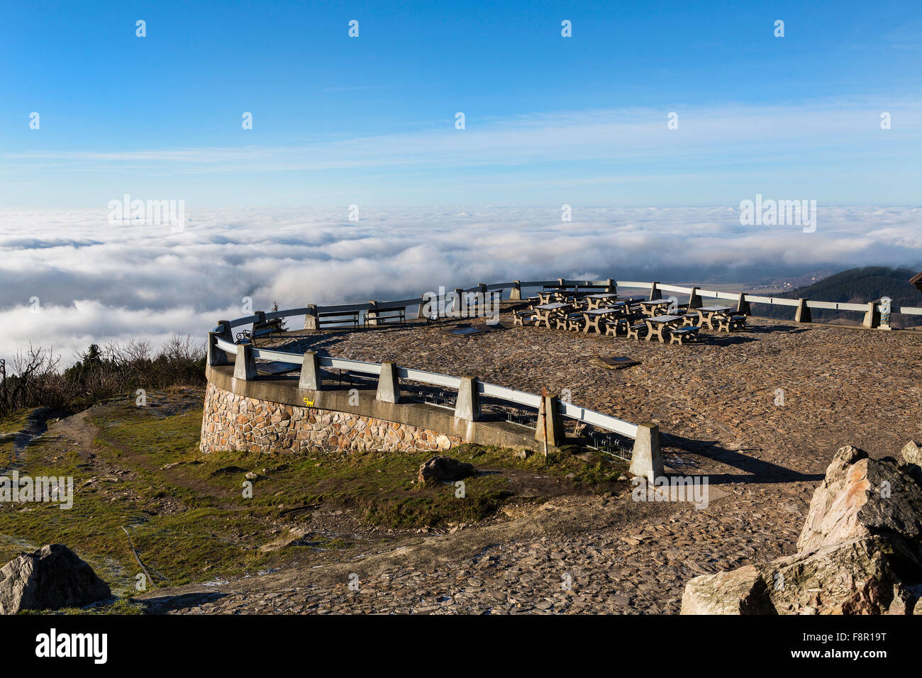 Terrazza in pietra che si affaccia l'inverso delle nuvole e la valle, panchine e tavoli di legno. Foto Stock