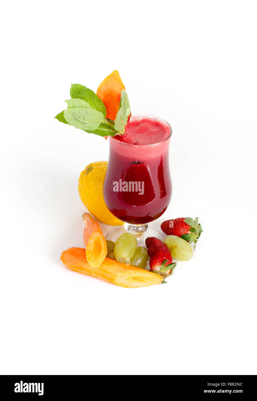 Close-up di uragano bicchiere pieno con una spessa cremisi bevanda opaco, decorate con una fetta di carota e le foglie di menta e raw Foto Stock