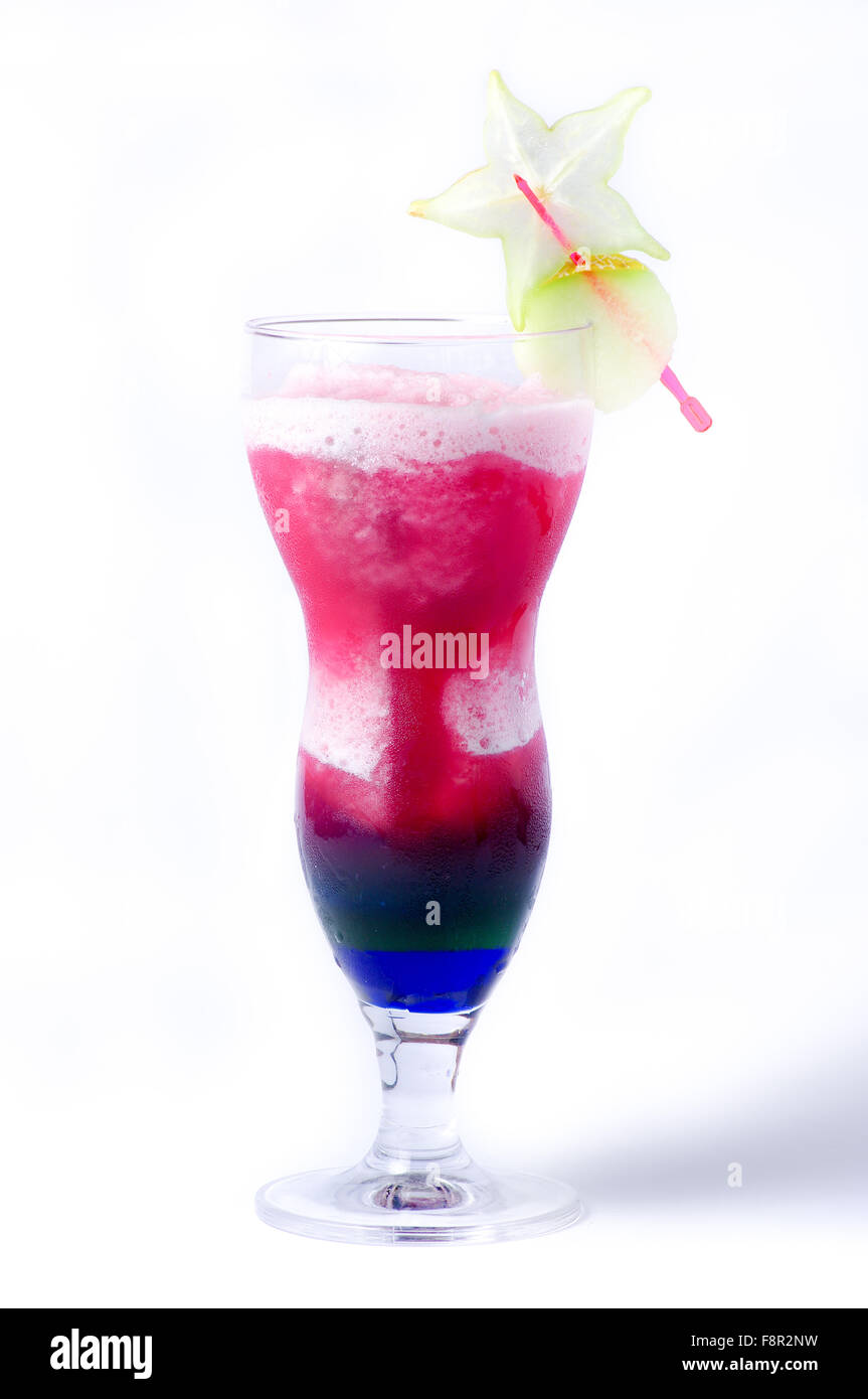 Close-up di un uragano bicchiere pieno con un cocktail a strati, costituito da una schiuma bianca, rosa e sciroppo di liquore blu nella parte inferiore, Foto Stock