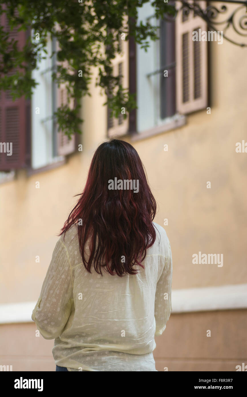 Vista posteriore di una giovane donna in piedi al di fuori di una casa Foto Stock