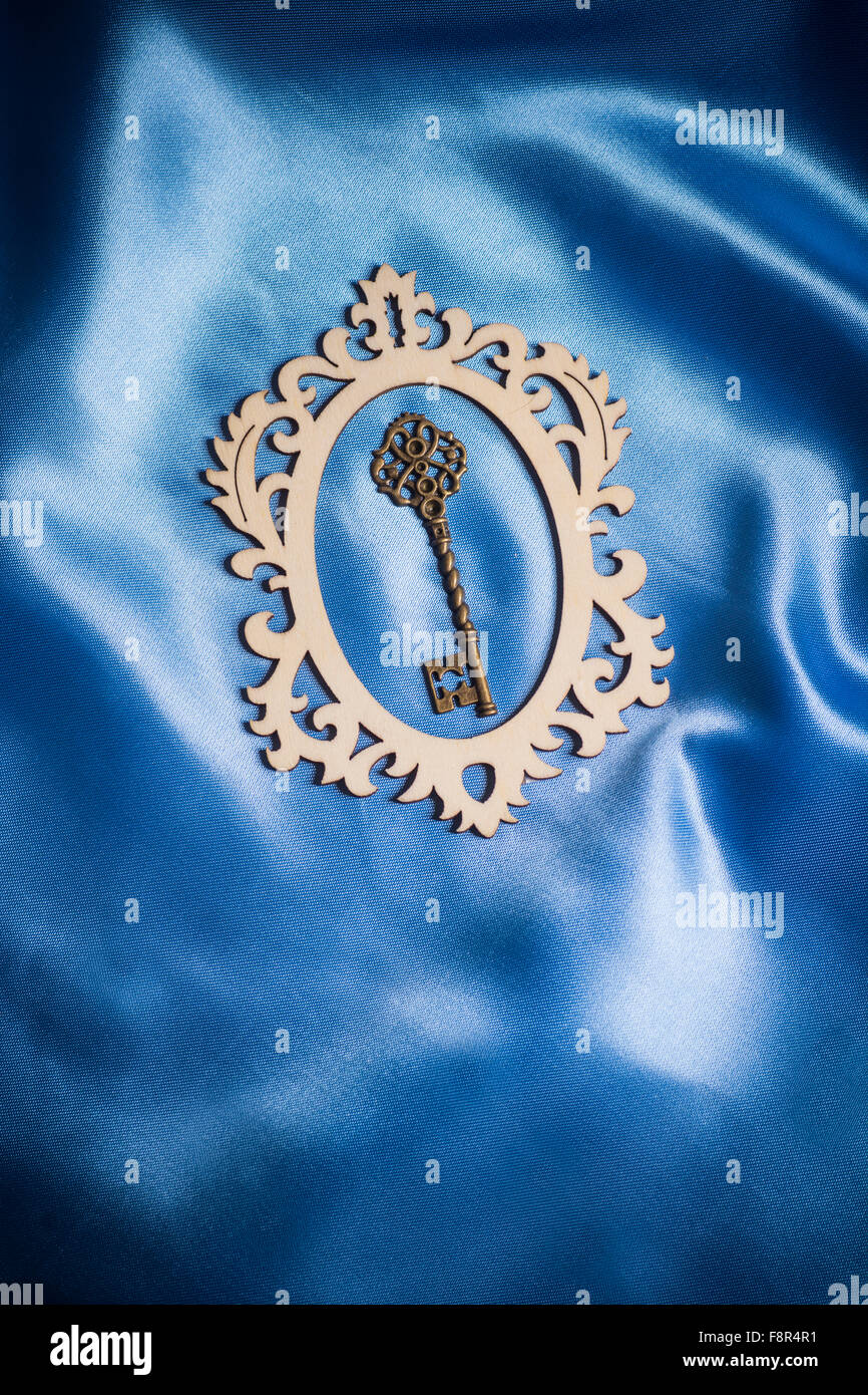 Chiave vintage all'interno di forma ovale ornato cornice su seta blu Foto Stock