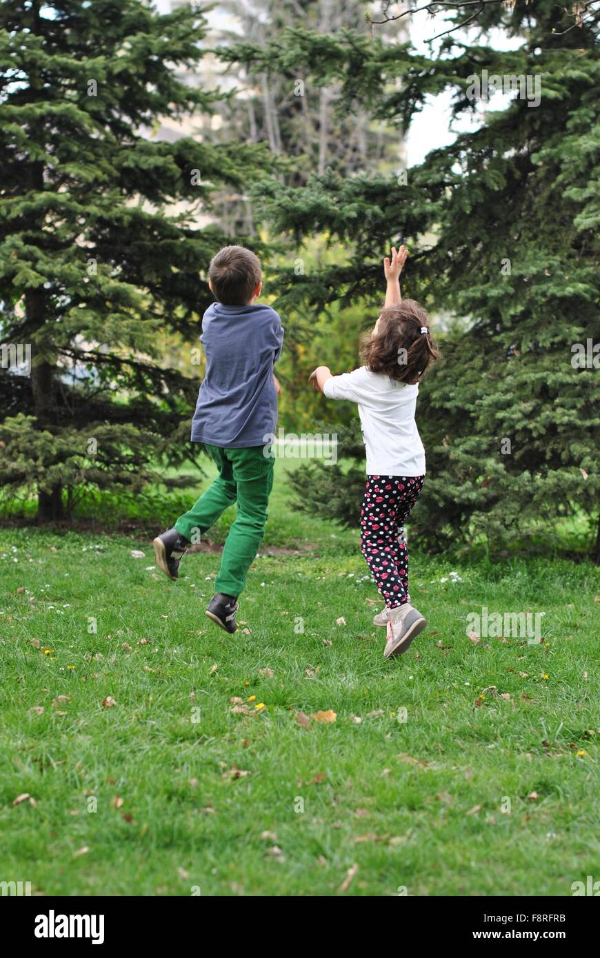Un ragazzo e una ragazza jumping dopo le bolle di sapone Foto Stock