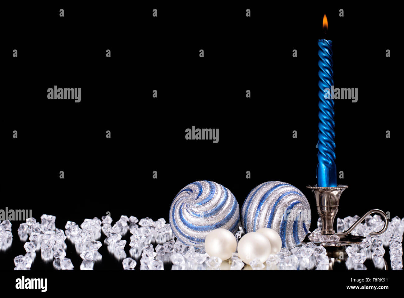 Argento candelabro con una candela blu e palle di vetro sorge accanto ad una moltitudine di pietre di cristallo sul mirror Foto Stock